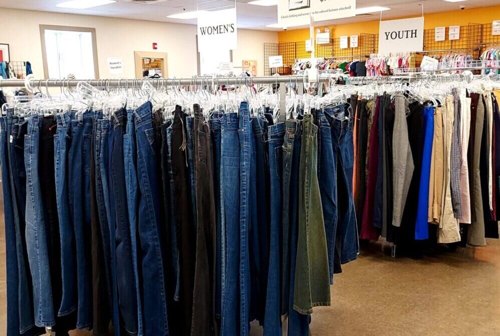 Huge selection of different used clothes for men, women and children on the  rack in a second hand shop or thrift store. Concept of waste problem in  fashion industry. Stock Photo