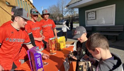 image of young baseball players donating boxes of cereal to the high school boys baseball teams food drive.