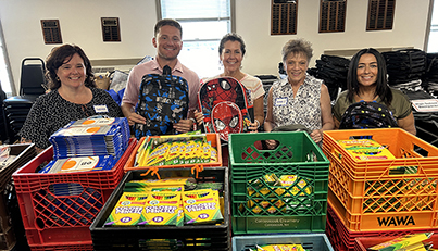 Volunteers help fill new backpacks for children