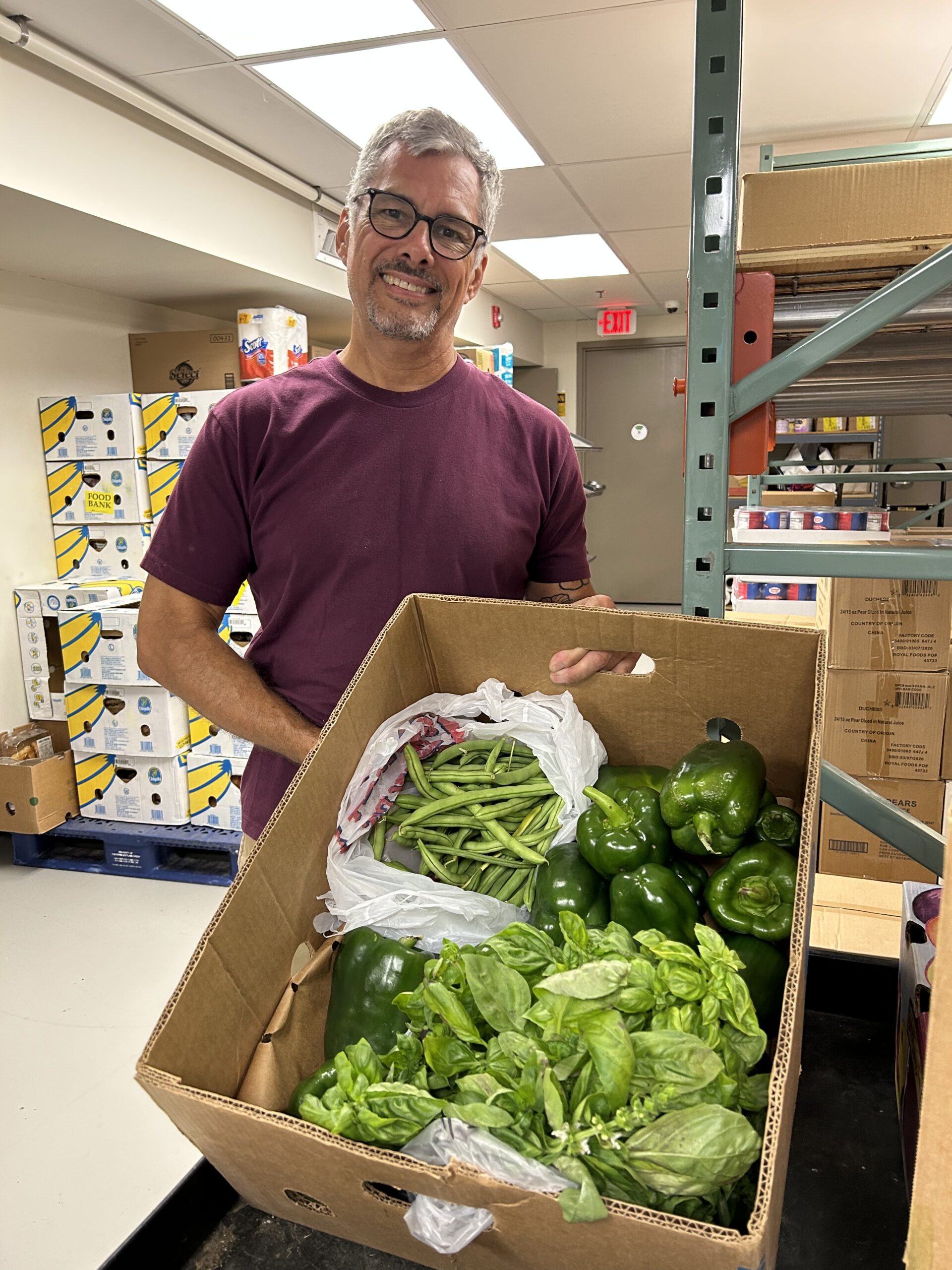 Mike from the Food Assistance team holding fresh, locally grown donated produce