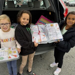 Girl Scouts holding up birthday kits they built to donate