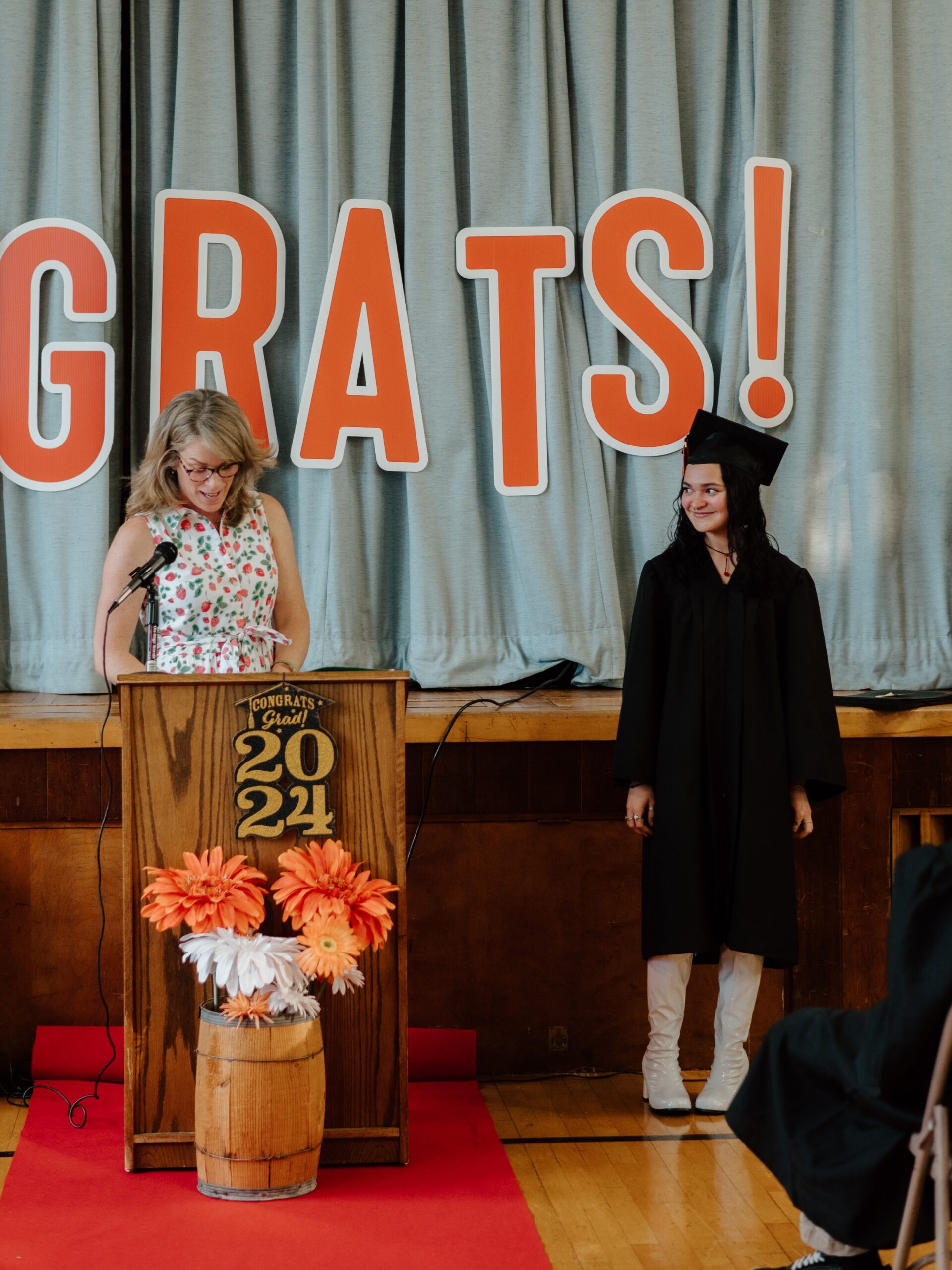 1 Belle smiles on stage while being recognized at their High School Equivalency graduation ceremony.